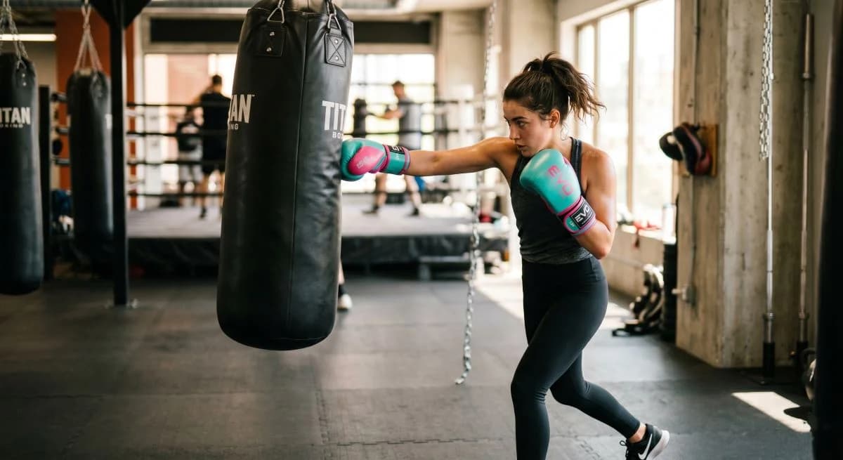 Women's beginner boxing gloves placed on a gym bench near hand wraps.
