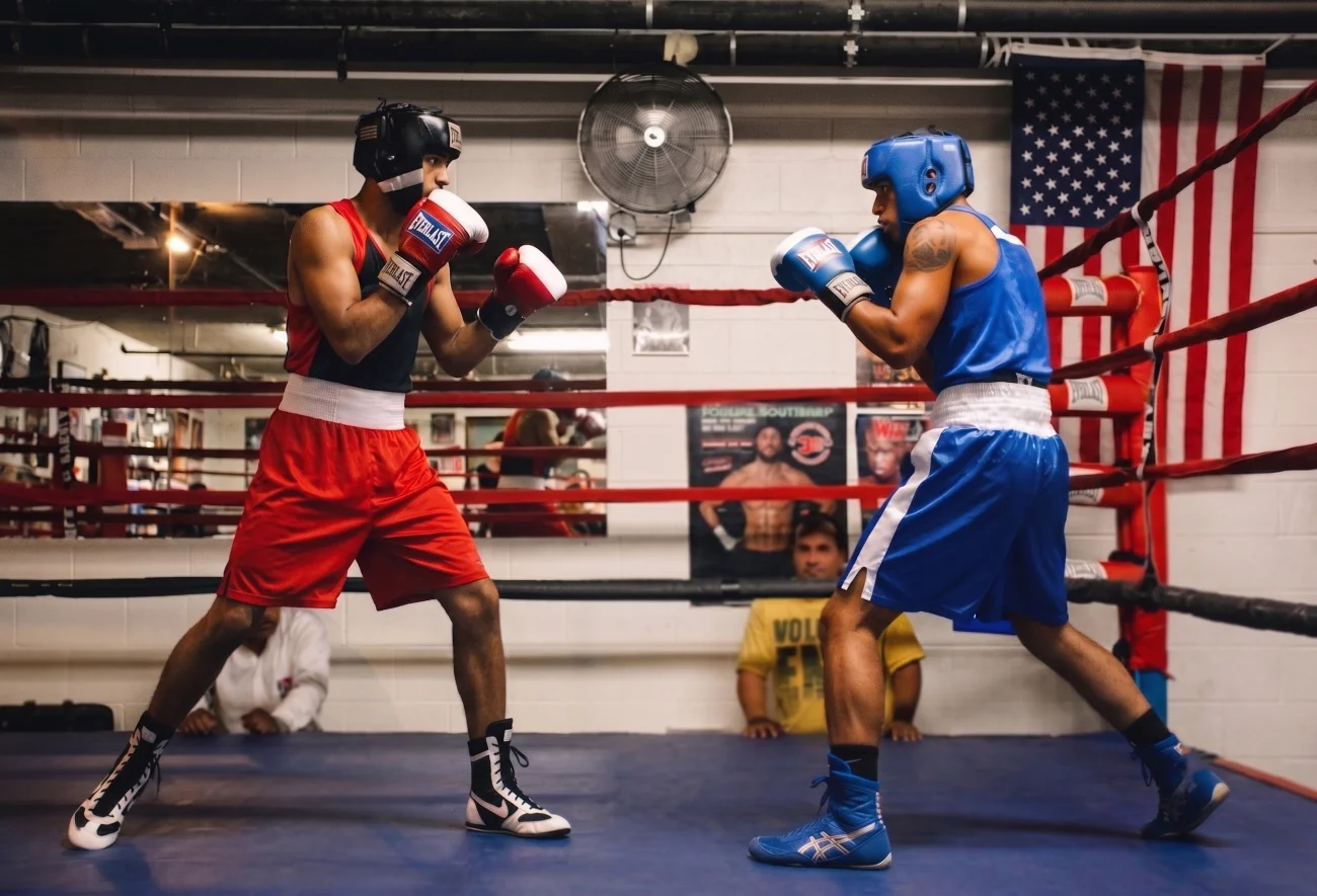 High top and low top boxing shoes side by side on a boxing gym floor