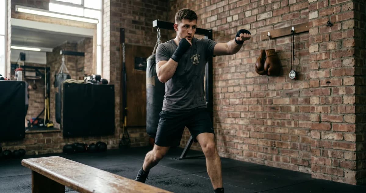 Beginner boxer shadow boxing in a gym while practicing stance, footwork, and punching technique.
