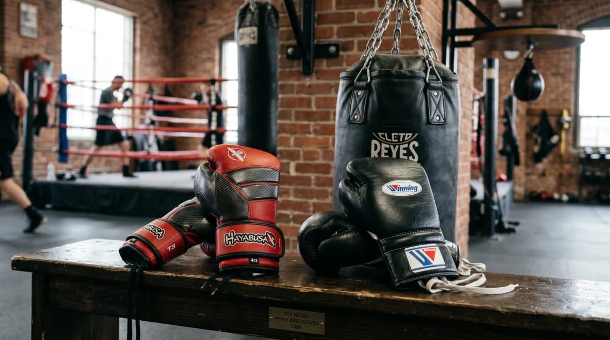 Boxing gloves resting beside a heavy bag in a boxing gym before training